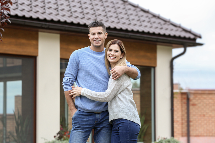 Personal Insurance - Happy Couple Standing in Front of Newly Purchased House